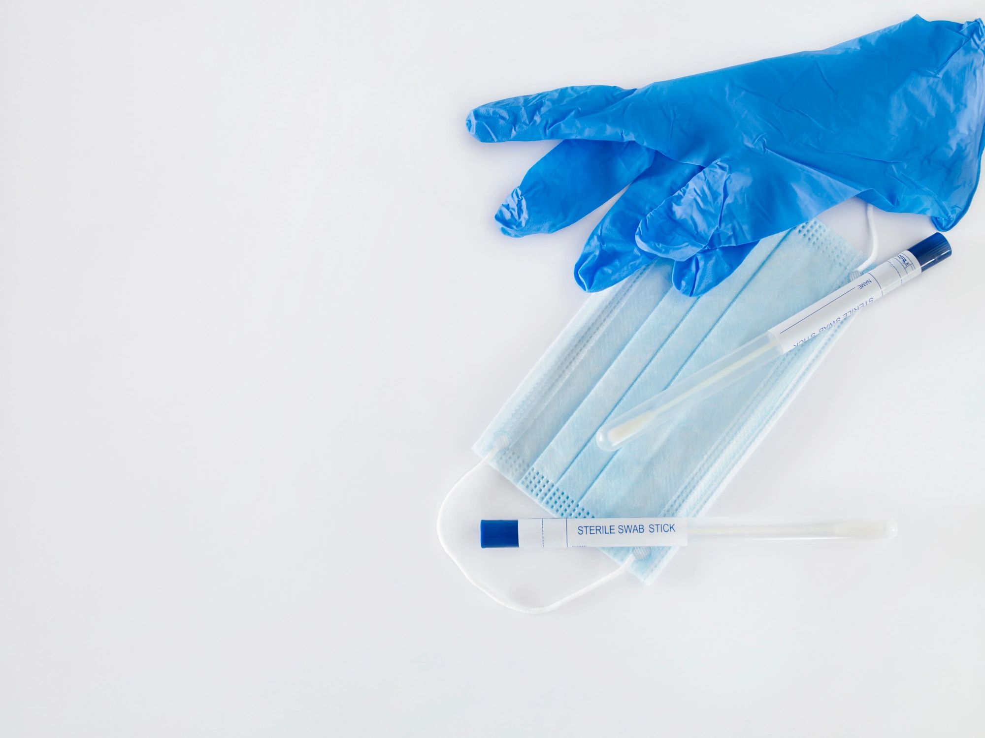 Medical consumables including gloves, mask, and diagnostic tools on a white background